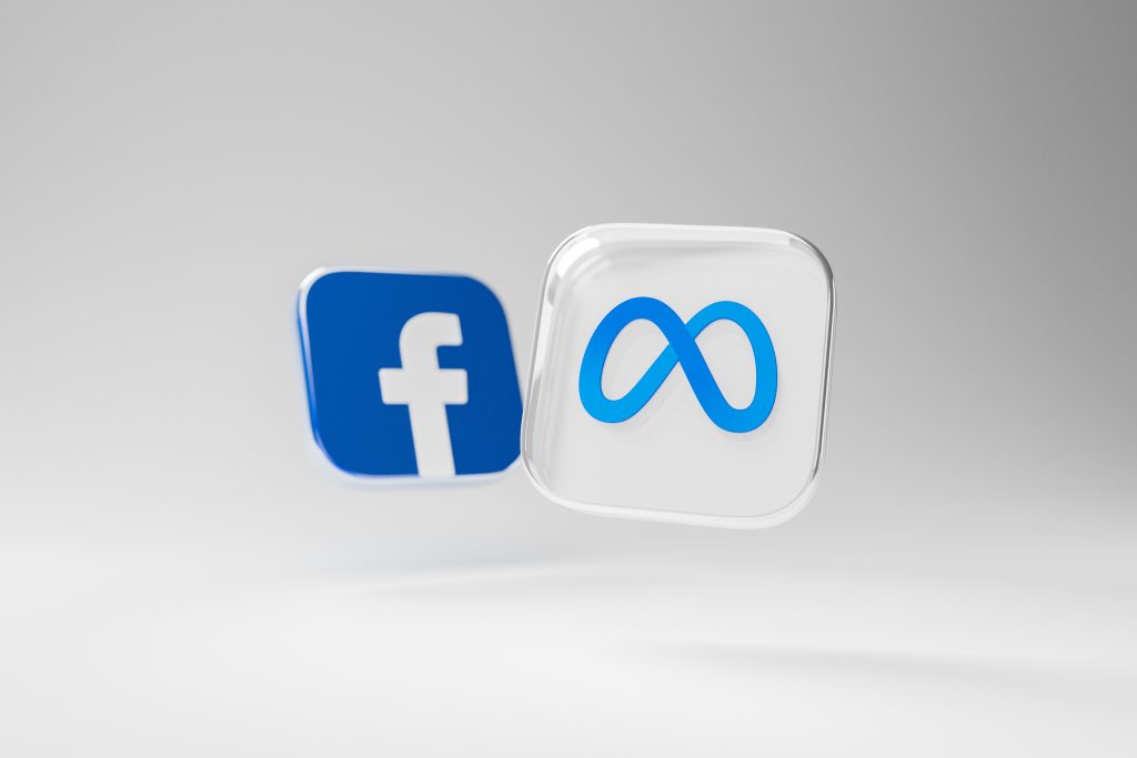 A 3D render featuring two logos: the Facebook logo, a white 'f' on a blue background, and the Meta logo, a stylized blue infinity symbol on a white background. Both icons appear to be floating against a light gray gradient background. The image visually represents Facebook and Meta platforms, which are key tools for managing Meta Ads and campaigns through Meta Ads Manager